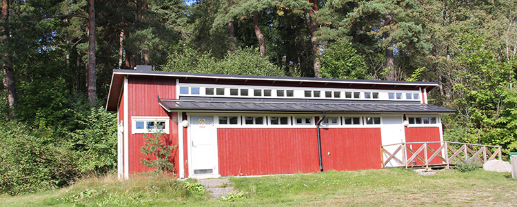 En röd träbyggnad med vita knutar och grå dörrar.