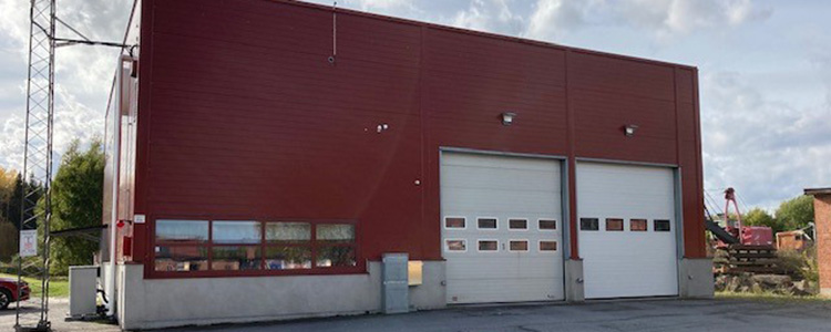 Skyttorps brandstation - en röd byggnad med två stora vita garageportar till höger.