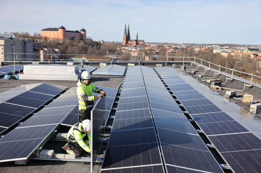 Två montörer håller upp solcell vid installation på Studenternas tak