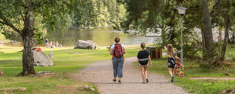 En vuxen och två barn går på en gångväg ner mot sjön.