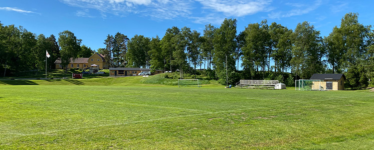 Vattholma idrottsplats, en inhägnad gräsplan med träd utmed sidorna